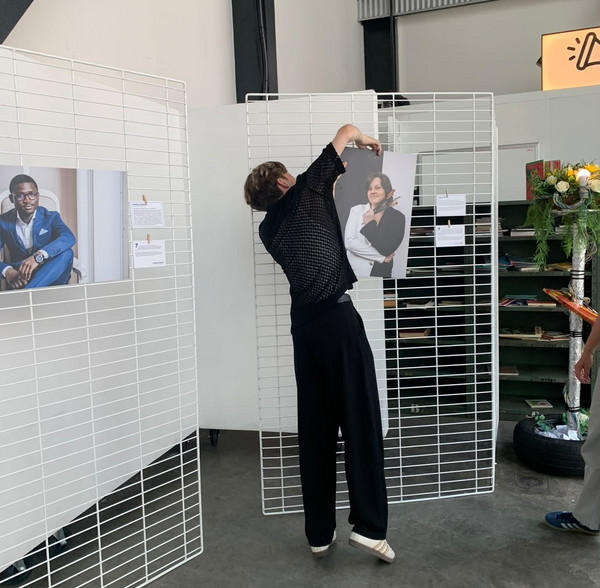 Photo montrant l'un des étudiants du projet en train d'acccrocher une photographie à l'aide de crochet.